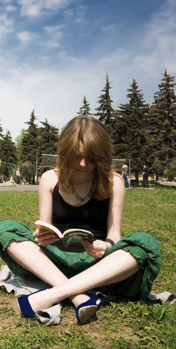 Ein Mädchen liest ein Buch im Freien